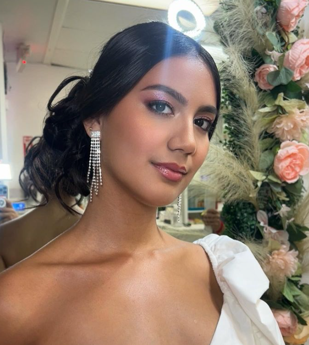 A woman in a white dress is standing in front of flowers