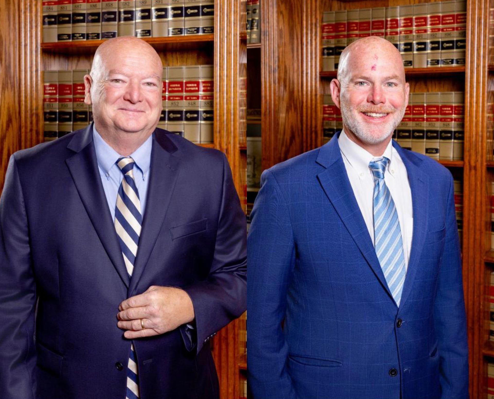 Two men in suits standing in front of a bookcase, smiling.