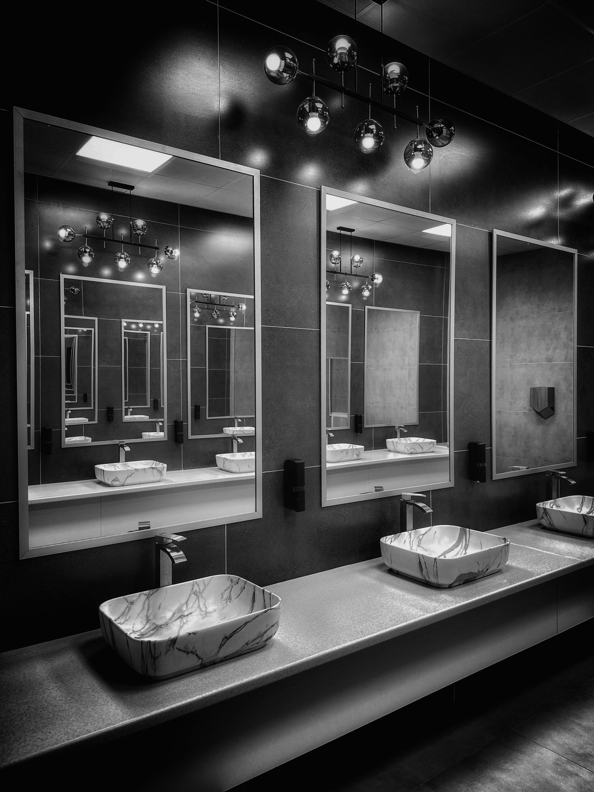 A black and white photo of a bathroom with sinks and mirrors
