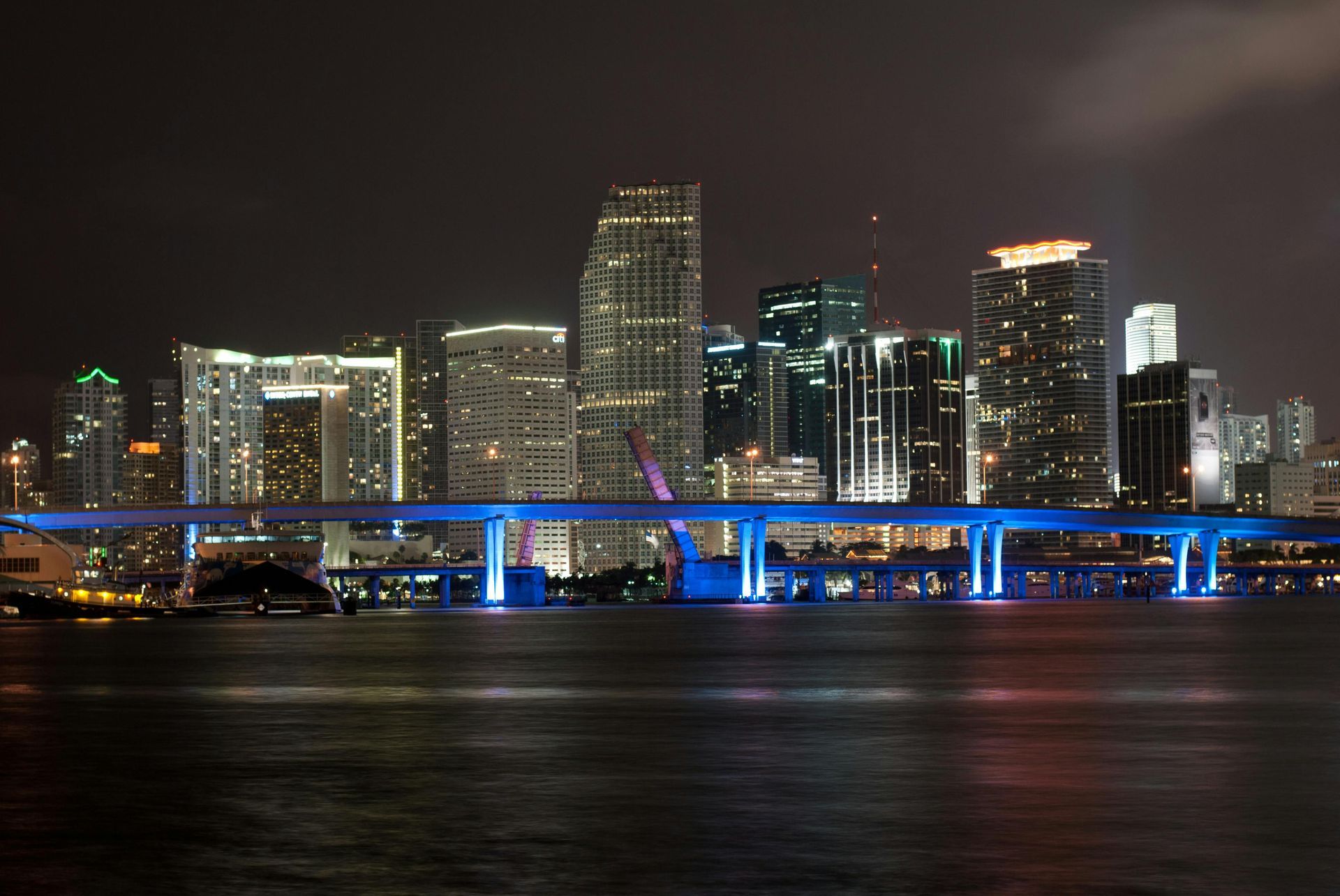 A city skyline at night with a bridge in the foreground