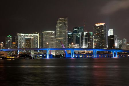 A city skyline at night with a bridge in the foreground