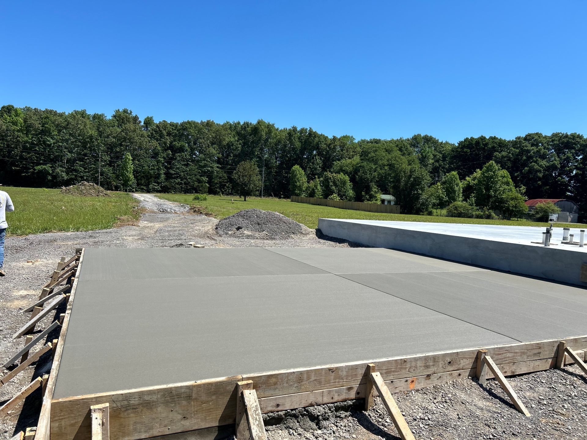 Concrete foundation slab being poured at a construction site under a clear blue sky