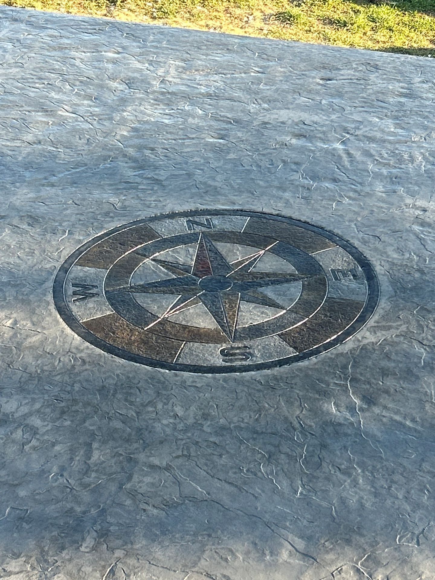 Compass rose emblem set into a textured stone surface outdoors