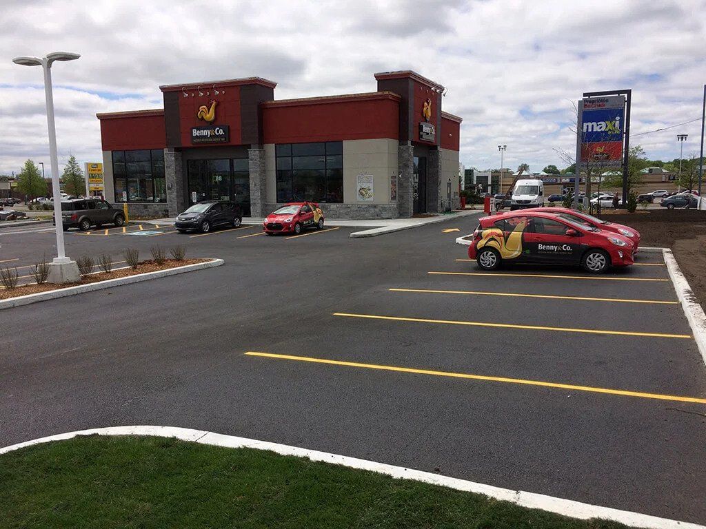 Une voiture rouge est garée devant un fast-food