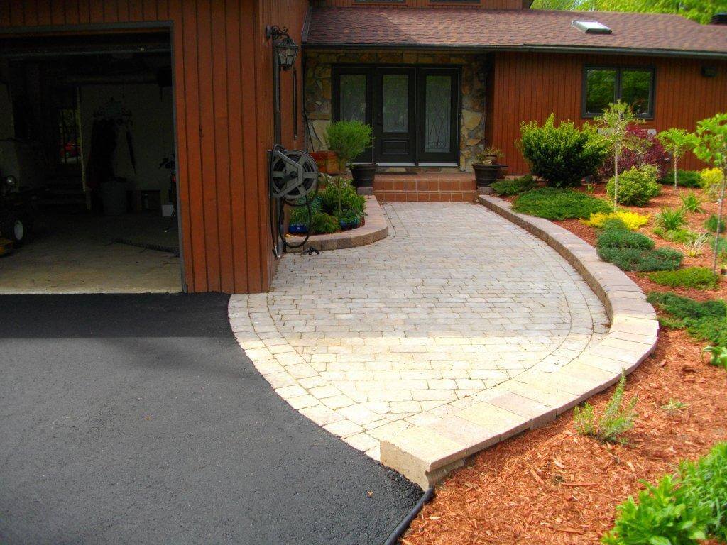 Une maison avec une passerelle en brique menant à la porte d'entrée.