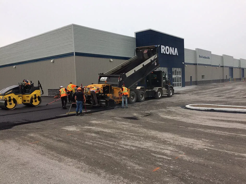 Un groupe d'ouvriers du bâtiment travaillent sur une route devant un grand bâtiment.