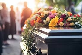 A man in a suit is sitting at a coffin at a funeral.