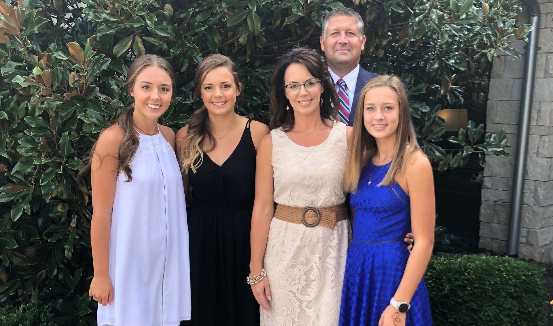 A family is posing for a picture together in front of a tree.