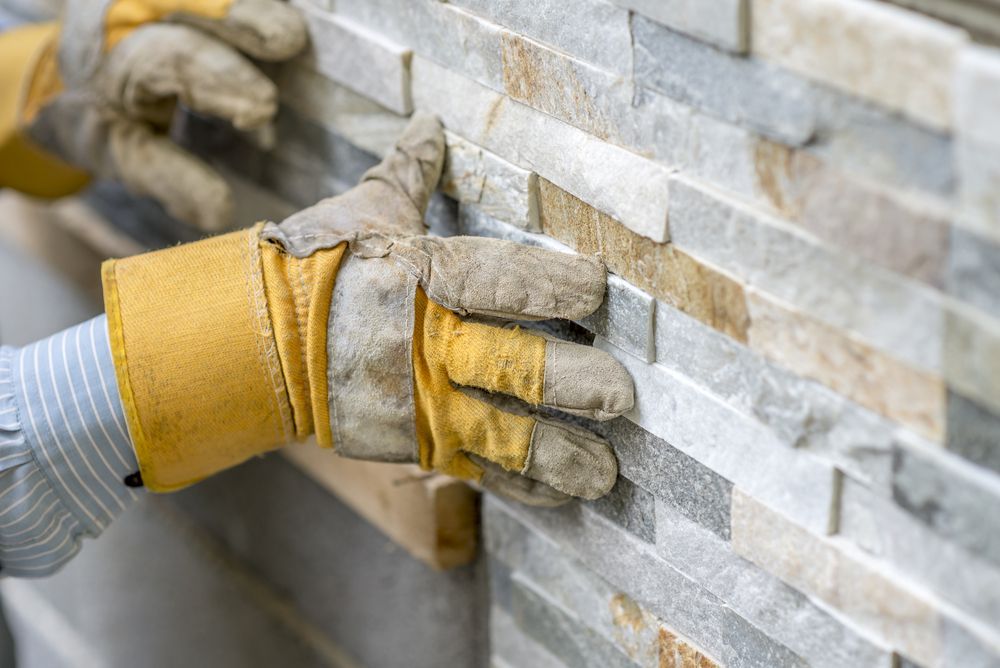A Close Up of Hand Pressing a Brick Onto Brick Wall — Ryan's Bricklaying In Eleebana, NSW