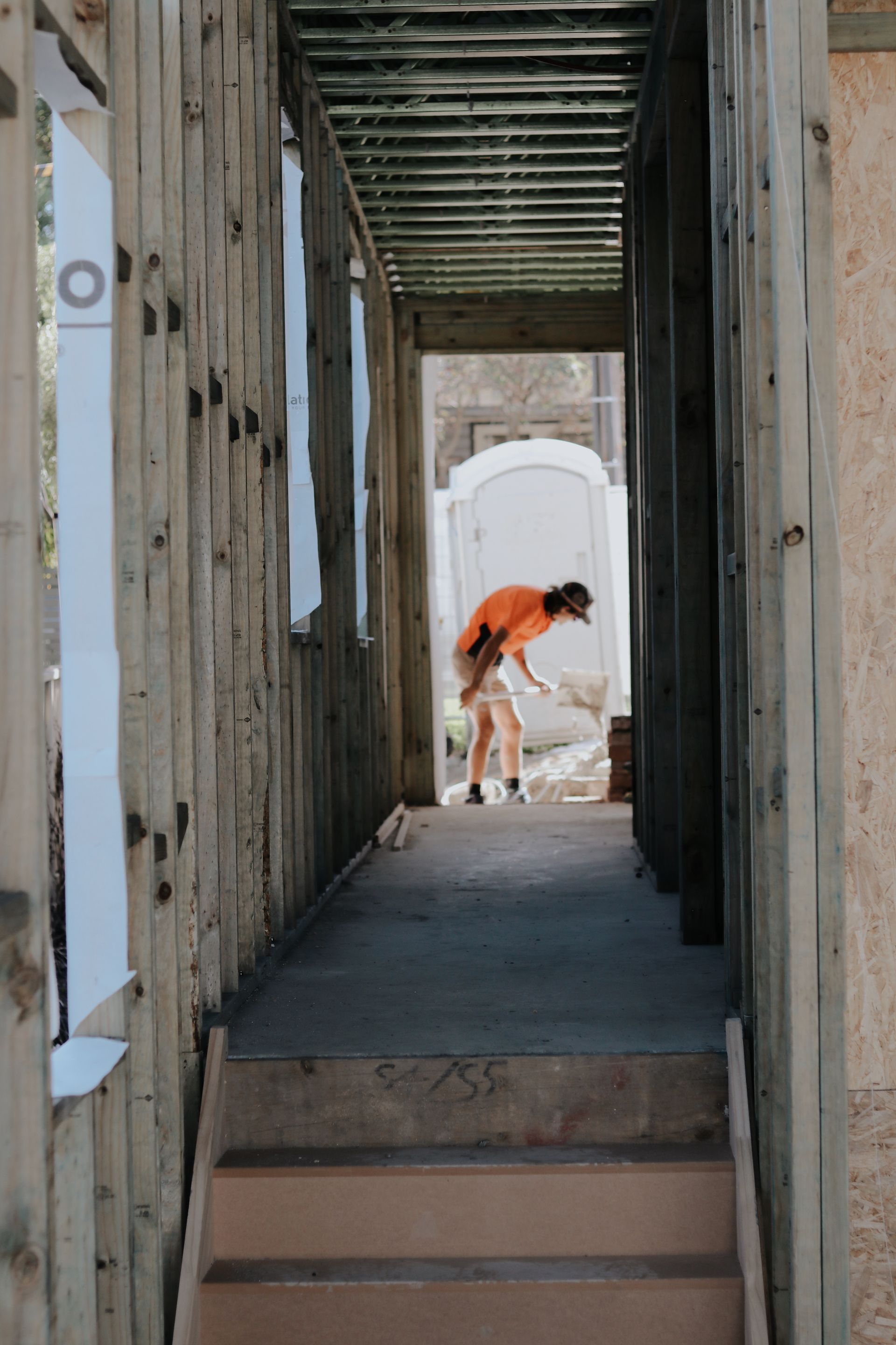 Construction Worker Near a Portable Toilet in a Building's Unfinished Hallway — Ryan's Bricklaying In Maitland, NSW