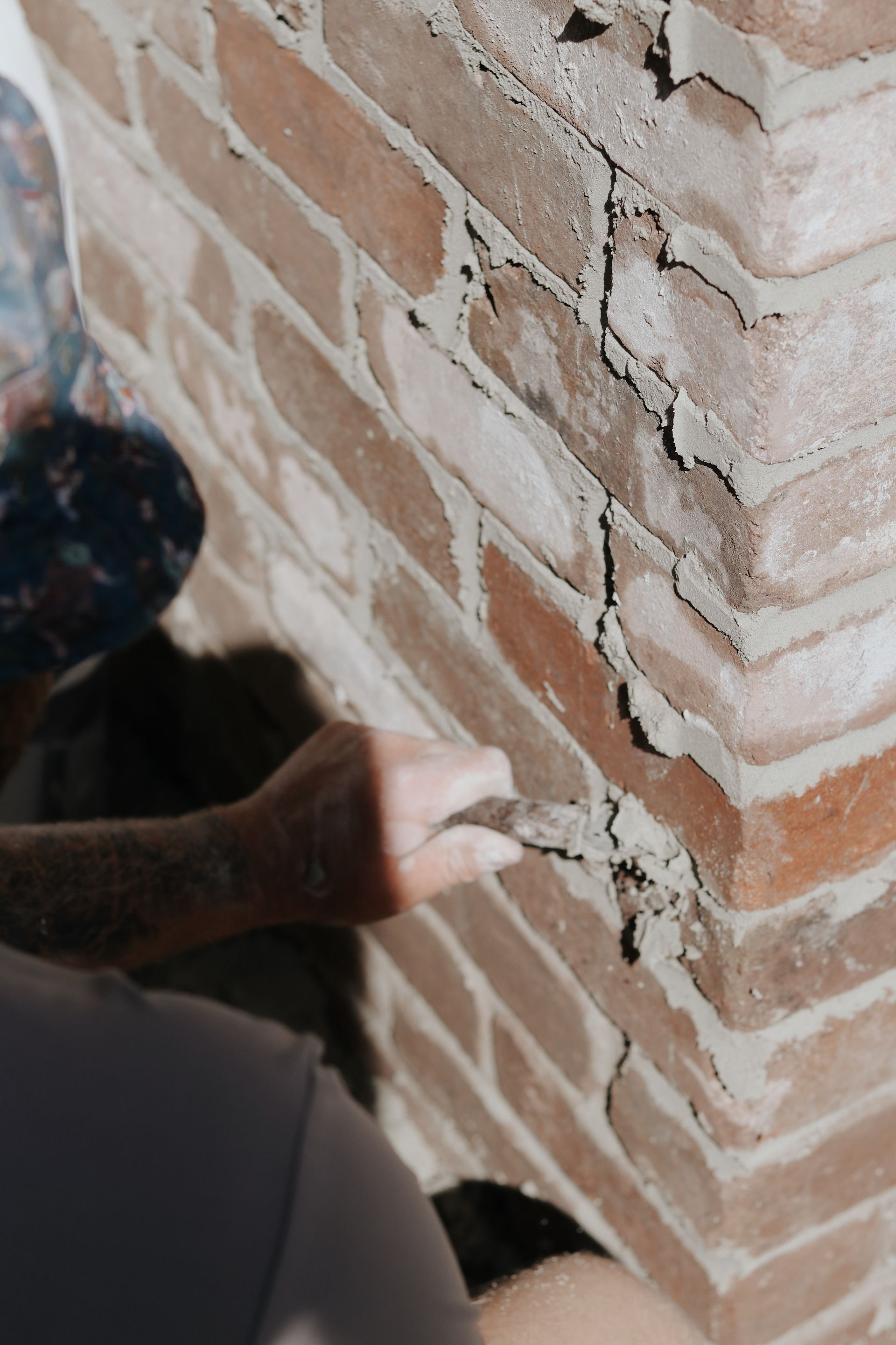 Person repairing a cracked brick wall with mortar— Ryan's Bricklaying In Eleebana, NSW