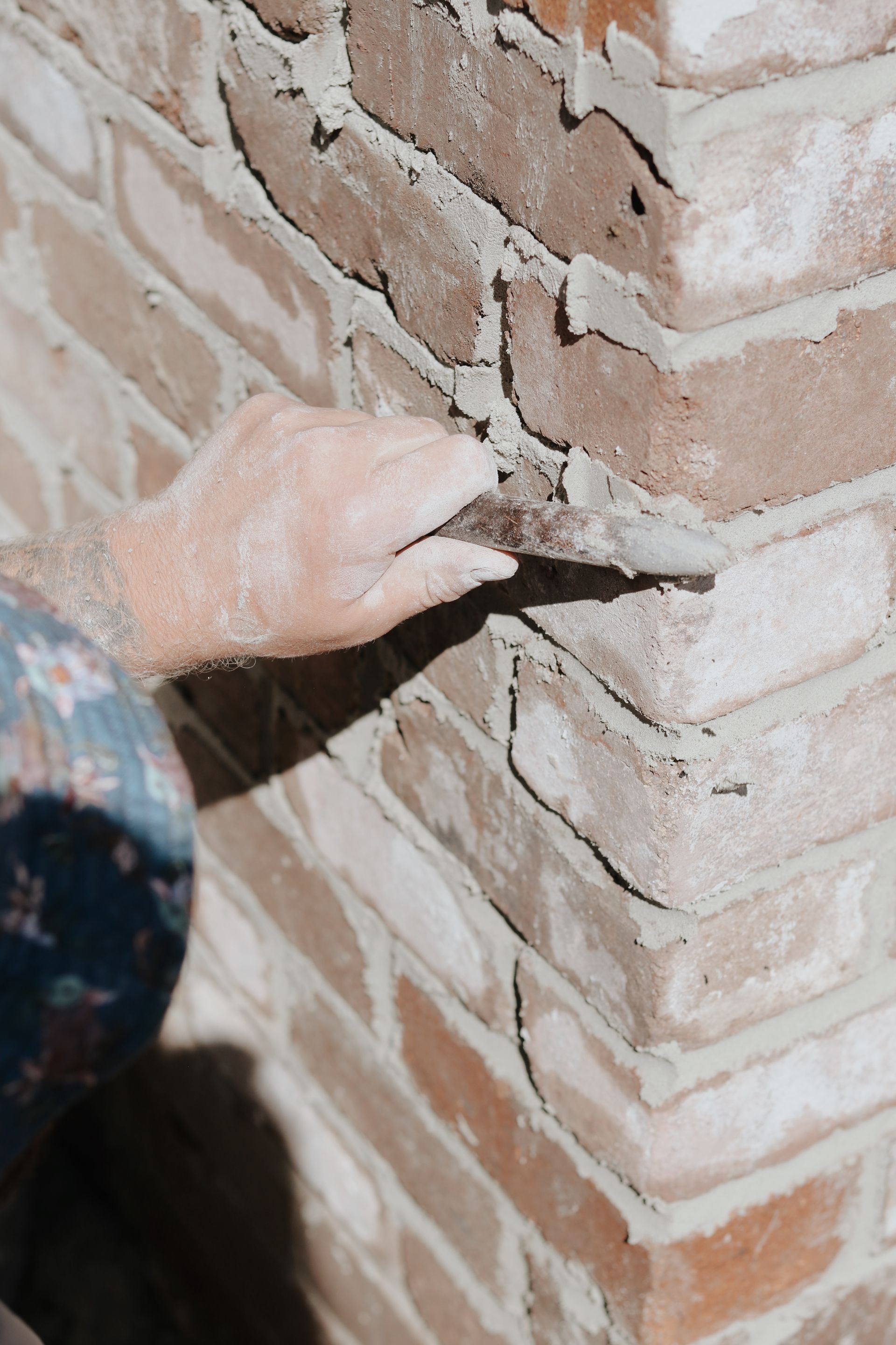 Hand Using a Trowel to Apply Mortar Between Brickwork — Ryan's Bricklaying In Lake Macquarie, NSW