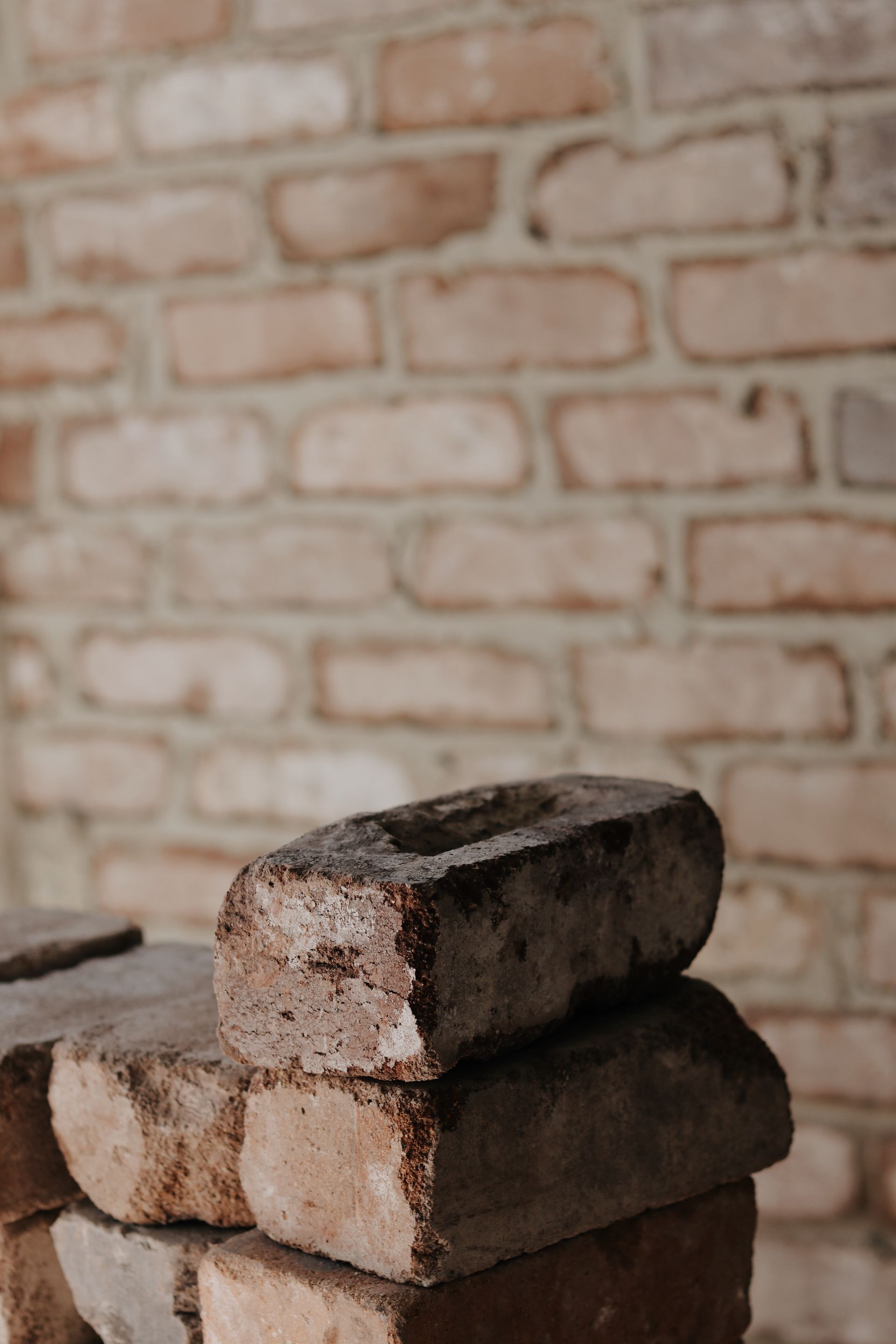 Stack of weathered bricks with a brick wall background— Ryan's Bricklaying In Eleebana, NSW