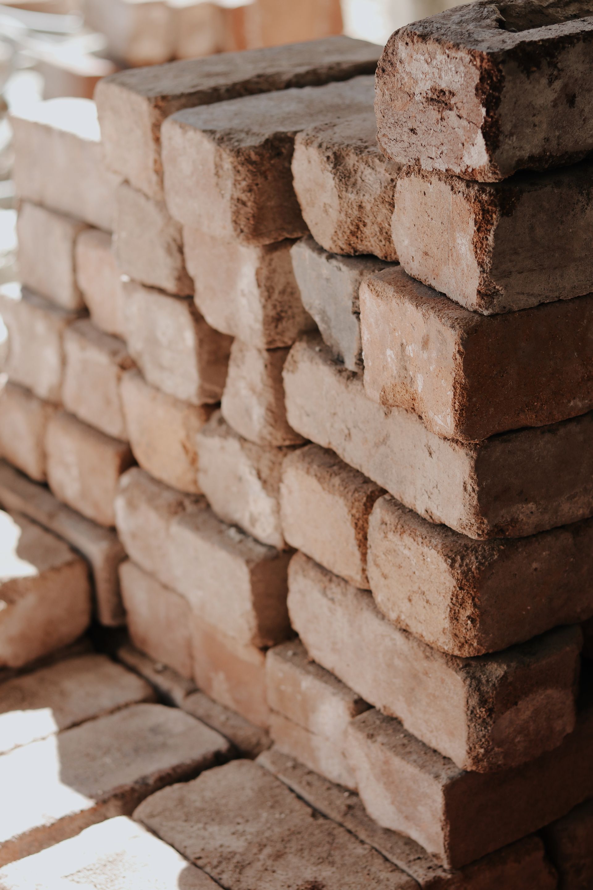 Pile of reddish-brown bricks, some in shadow, stacked neatly outdoors, ready for construction— Ryan's Bricklaying In Eleebana, NSW