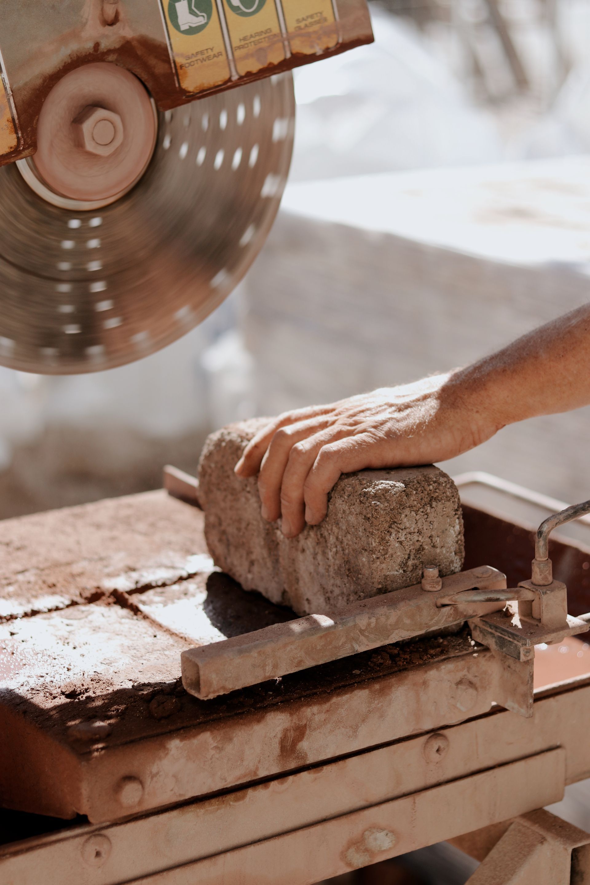 Person Using a Circular Saw to Cut a Stone Block — Ryan's Bricklaying In Eleebana, NSW