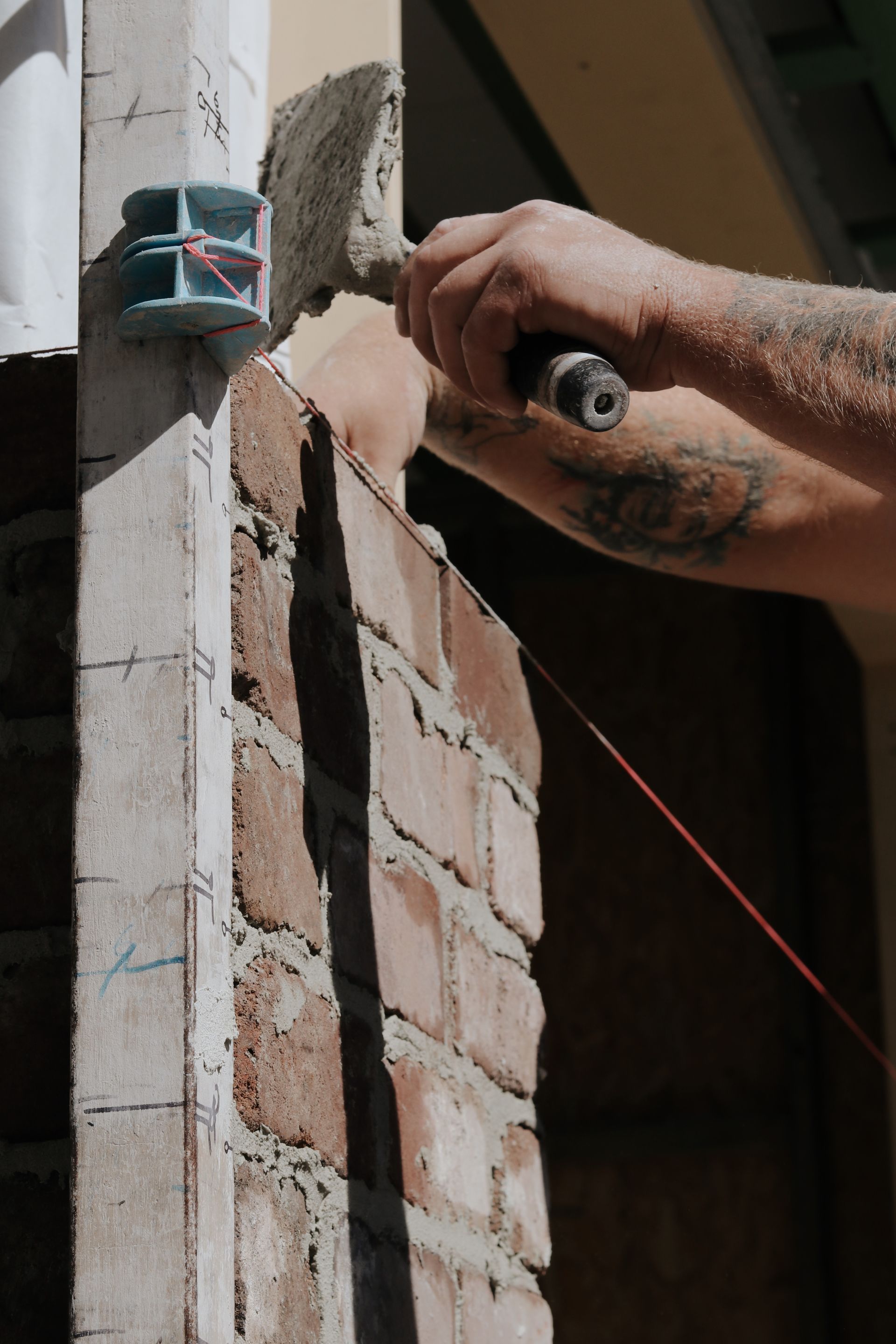 Two People Laying Bricks on a Sandy Surface — Ryan's Bricklaying In Huntlee, NSW
