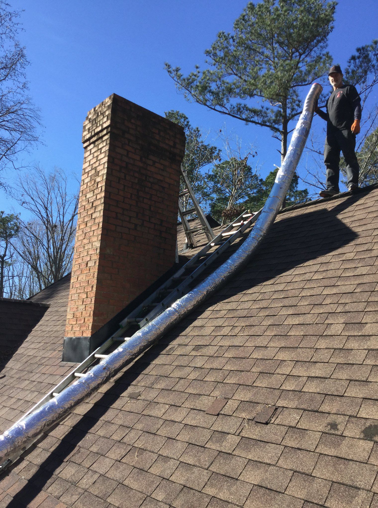 A man holding a tool for sweeping the chimney