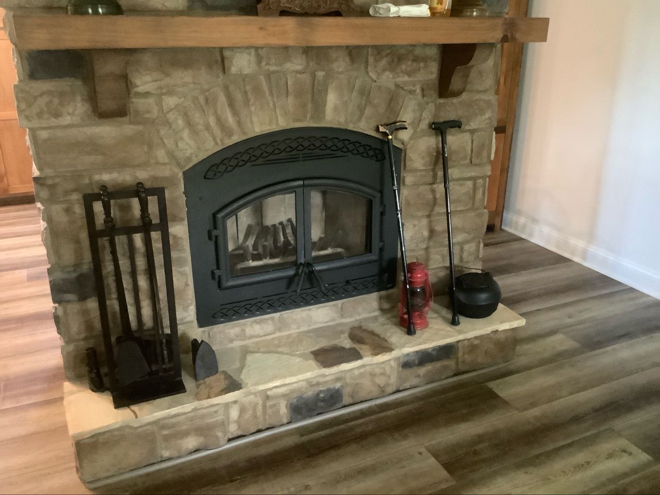 A fireplace with a black door and a wooden mantle in a living room.
