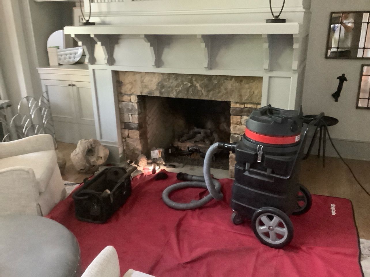 A vacuum cleaner is sitting in front of a fireplace in a living room.