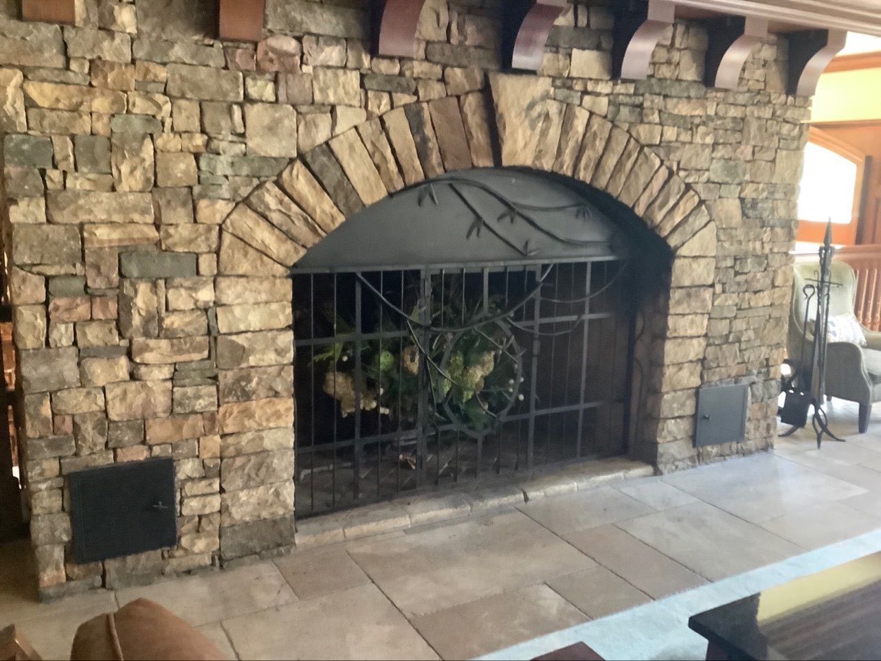 A stone fireplace with a wreath on it in a living room