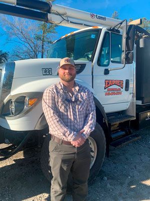 Man in cap stands by a white truck with 