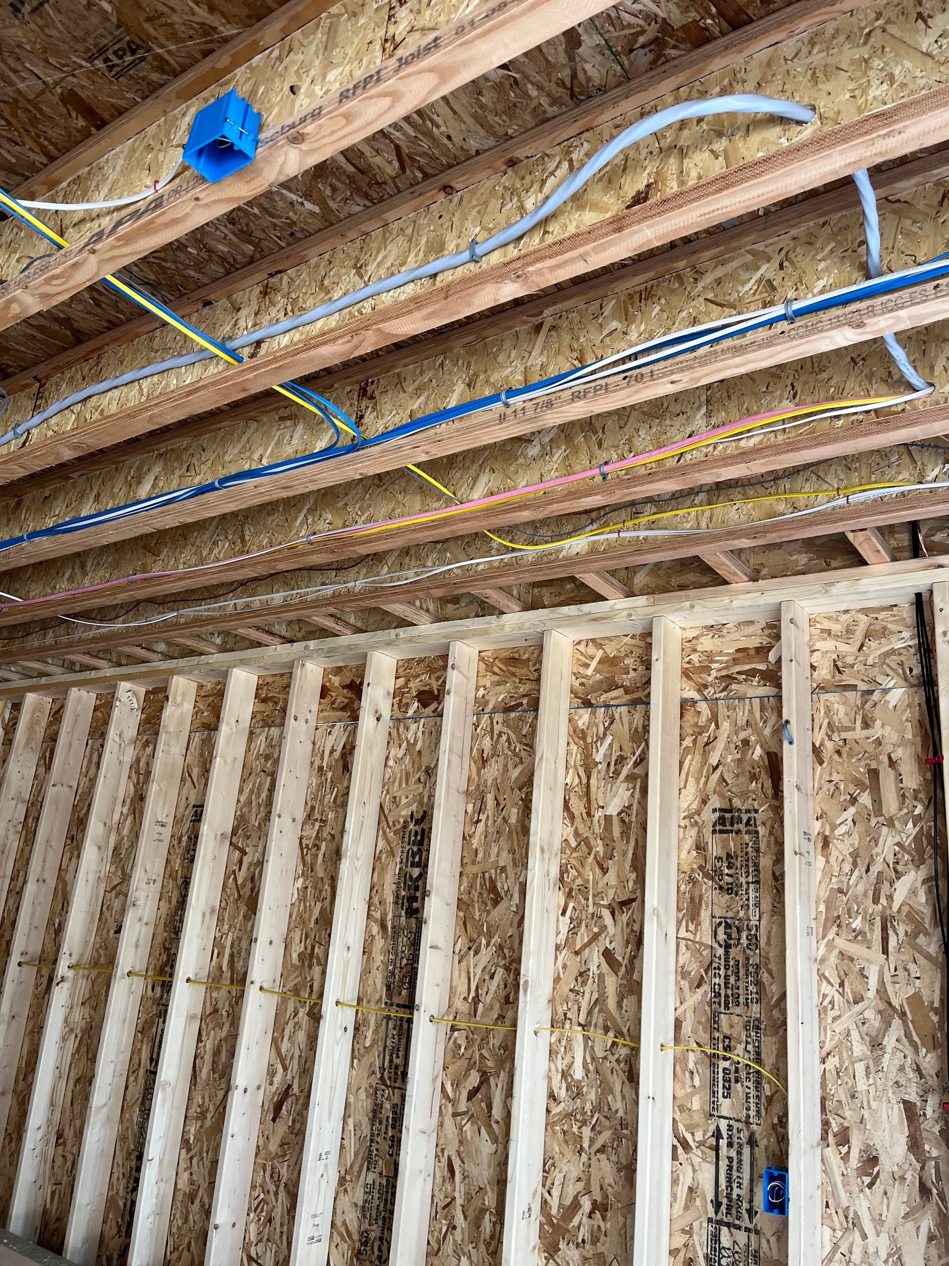 The inside of a house with electrical wires hanging from the ceiling installed by Patriot Electrical Solutions.