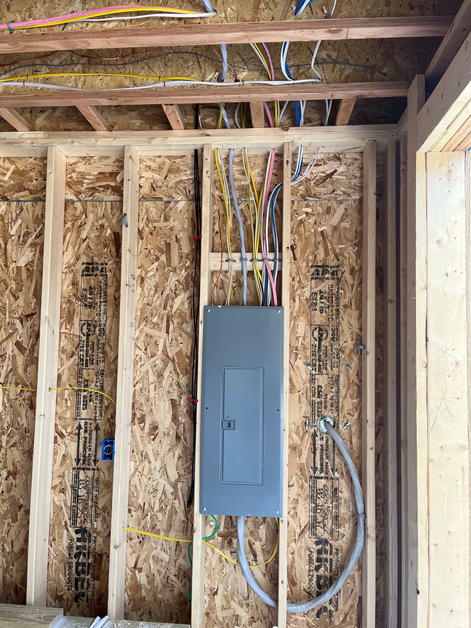 There is a electrical box on the wall of a house under construction by Patriot Electrical Solutions.