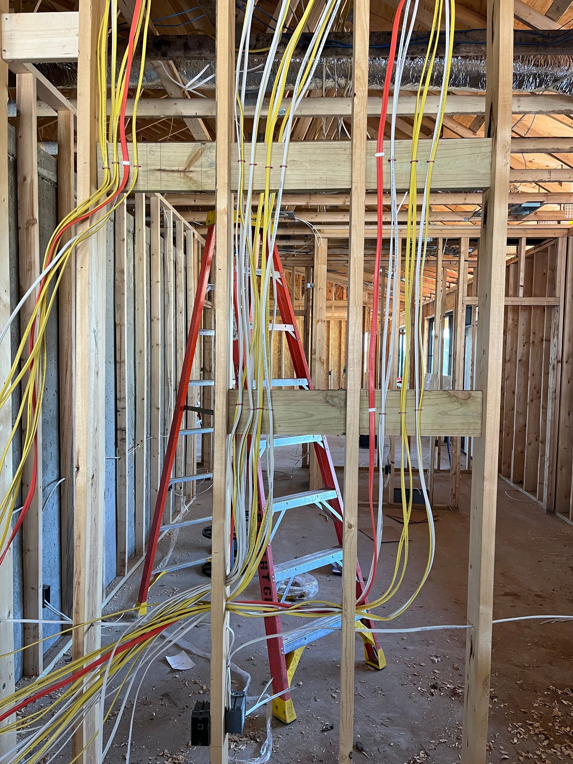 A ladder is sitting in the middle of a building under construction by Patriot Electrical Solutions.