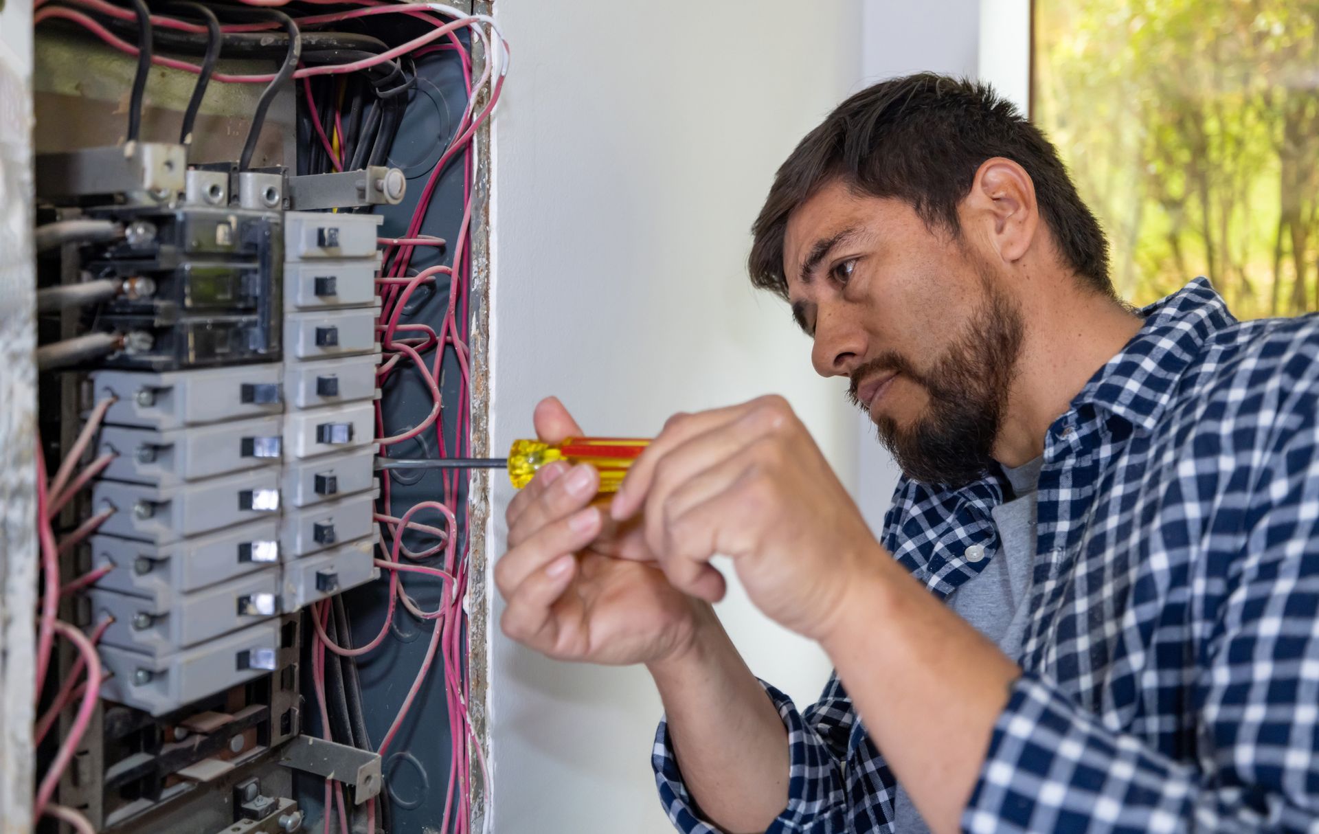 Electrician inspecting an electrical panel for upgrade warning signs in a residential home.