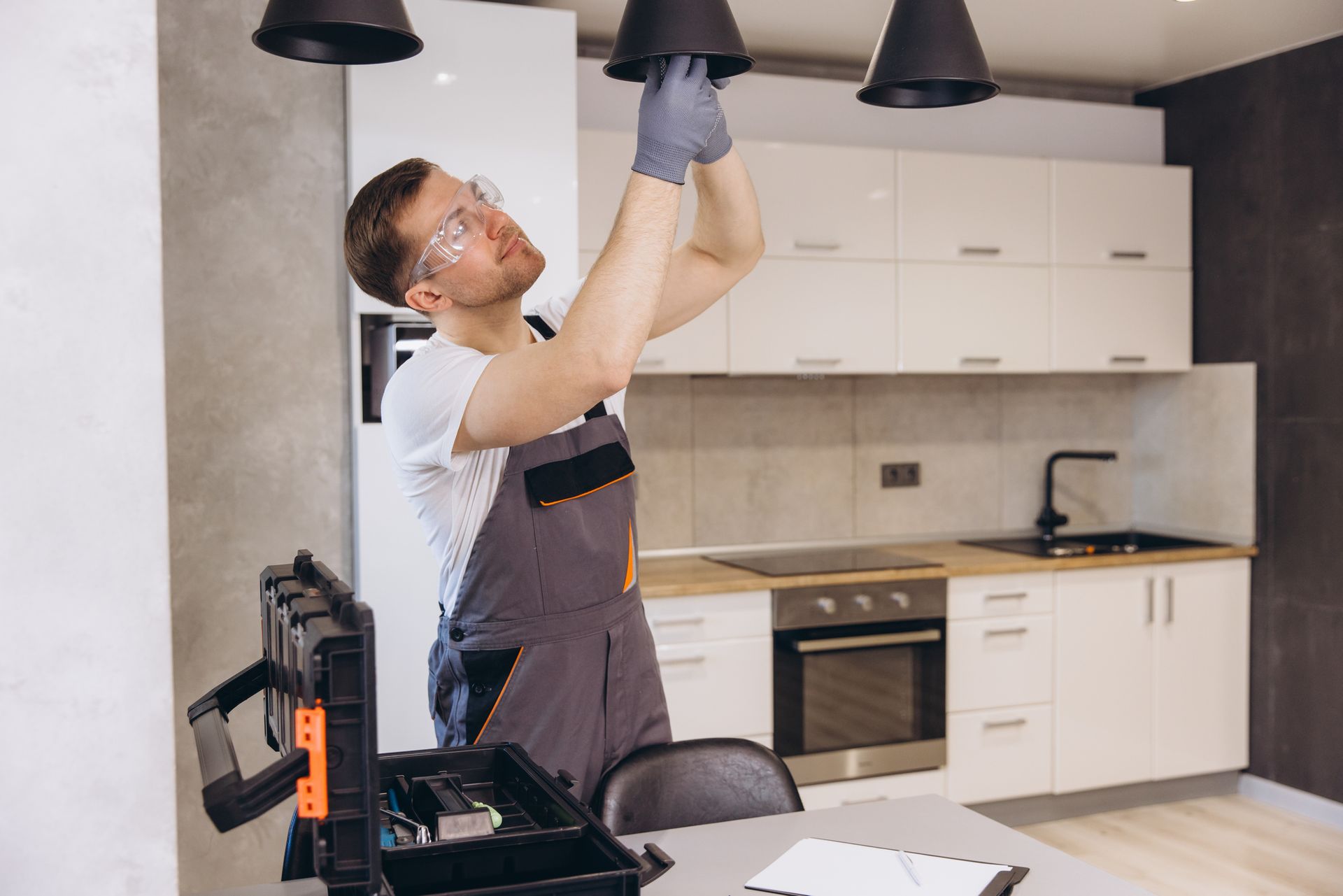 A man is fixing a light fixture in a kitchen.
