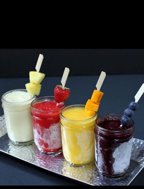 Four glasses of different flavors of smoothies on a silver tray