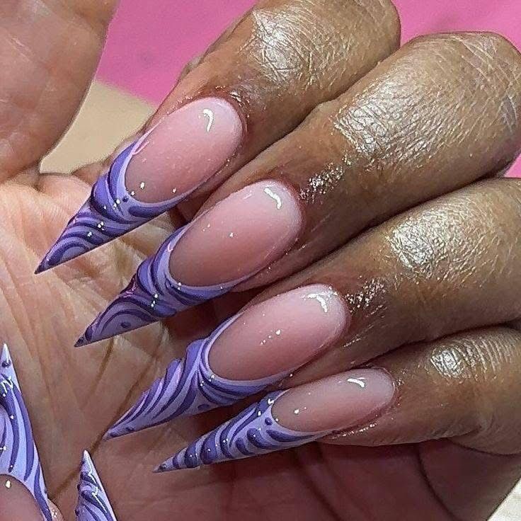 A close up of a woman 's nails with a purple design