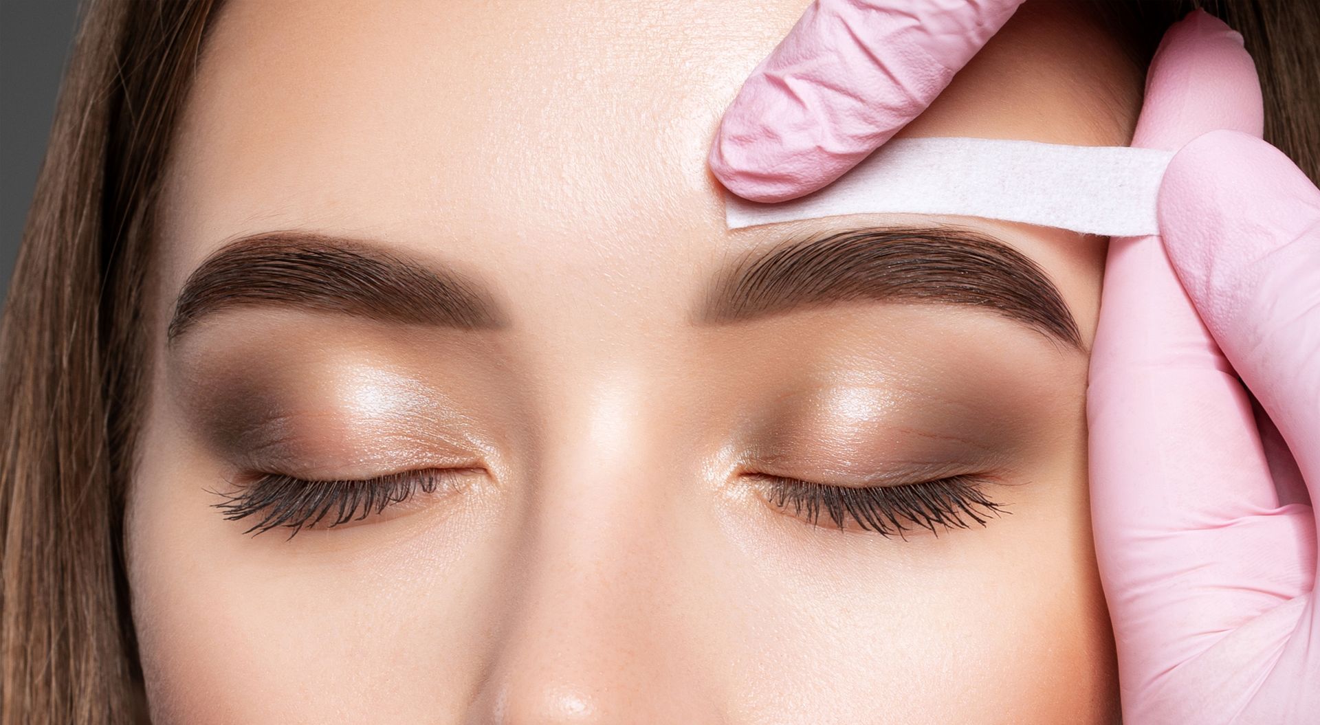 A close up of a woman getting her eyebrows waxed.
