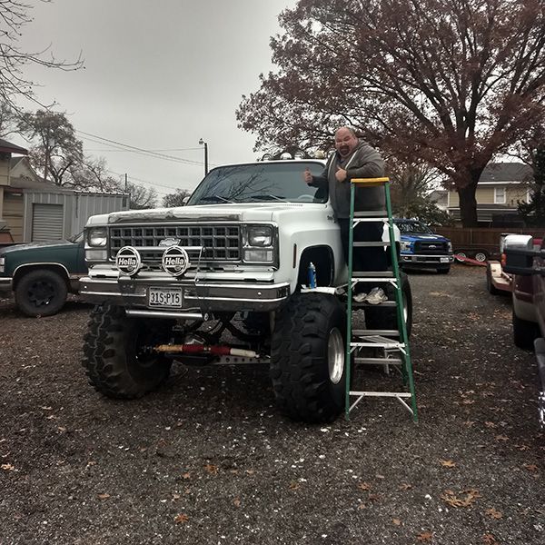 A man is standing on a ladder next to a truck