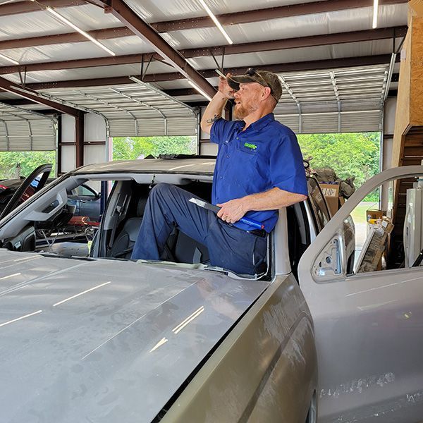 A man in a blue shirt is sitting on the hood of a truck