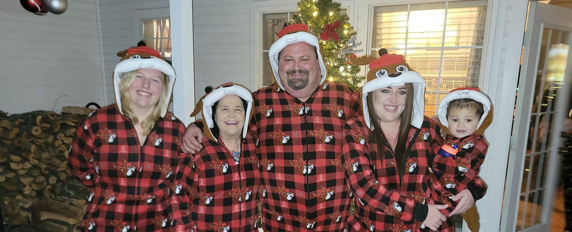 A family is posing for a picture in front of a christmas tree.