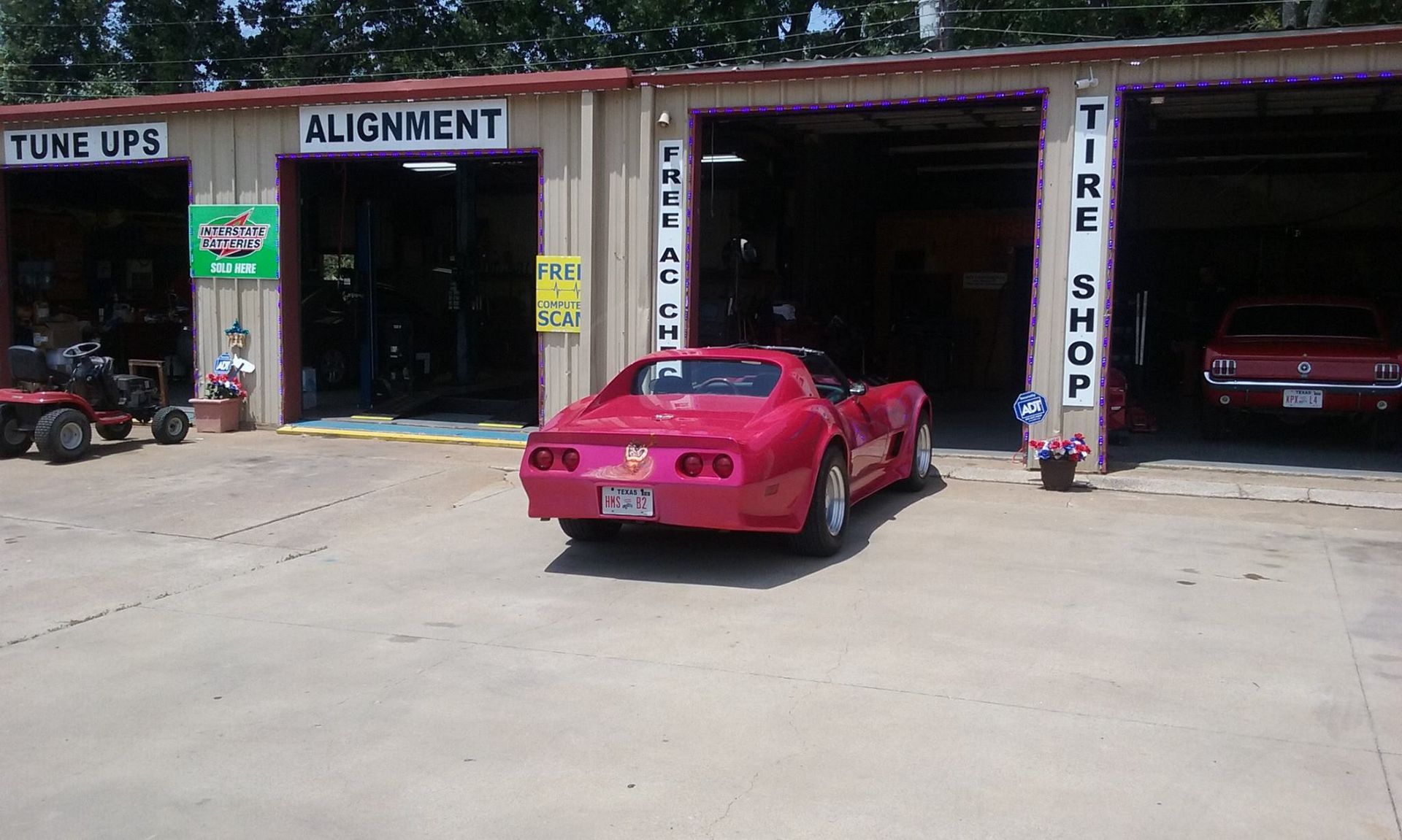 A red corvette is parked in front of a tire shop