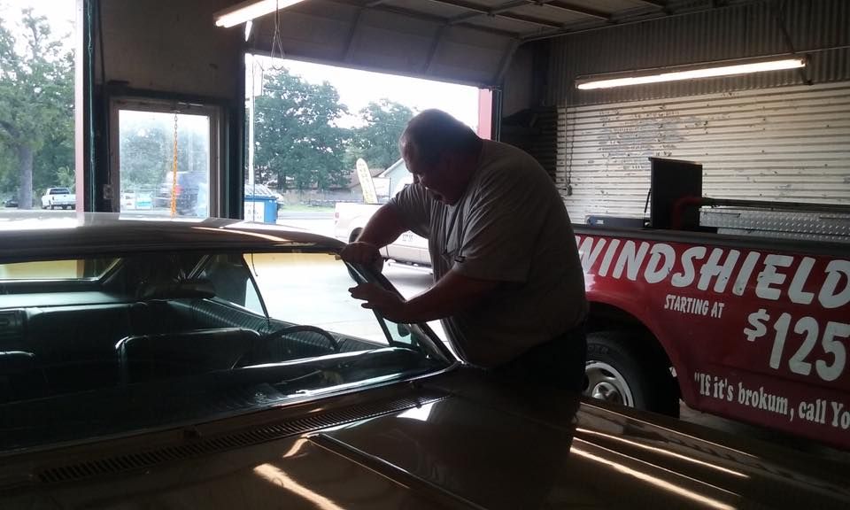 A man is working on a windshield in front of a truck that says windshield $ 125