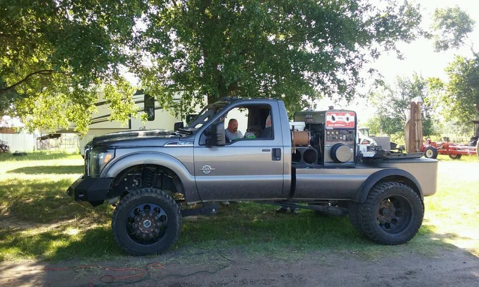 A truck with a generator in the bed is parked under a tree.