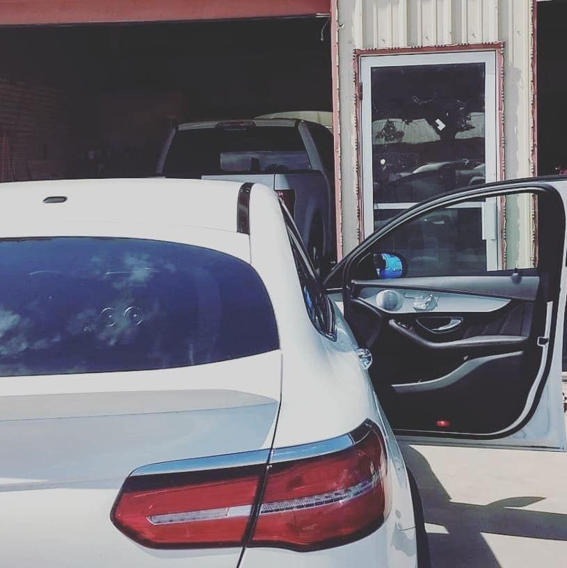 A white car is parked in front of a garage door
