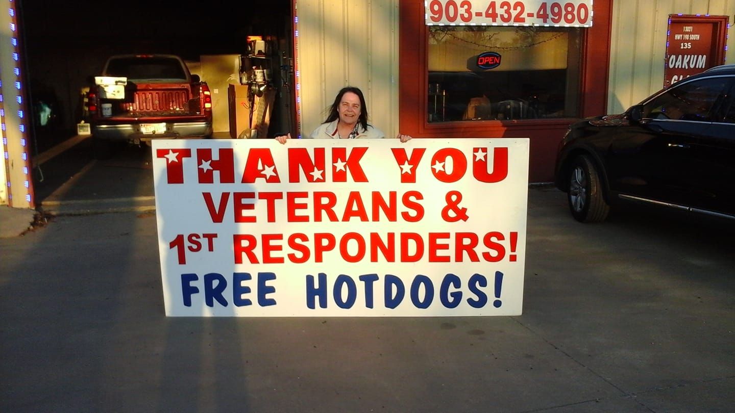 A woman holding a sign that says thank you veterans and 1st responders free hotdogs