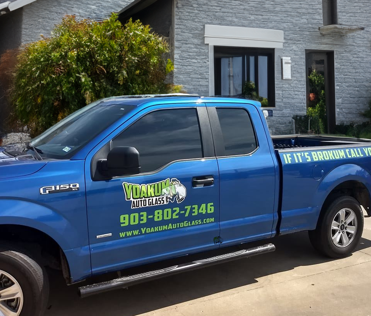 A blue truck is parked in front of a house