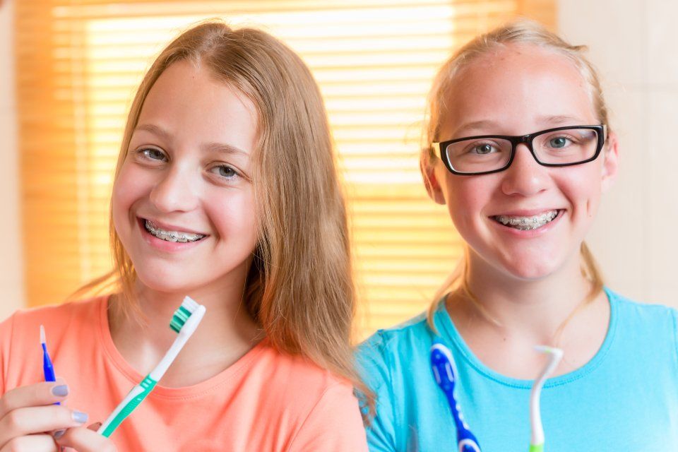 due ragazzine con apparecchio dentale e spazzolini