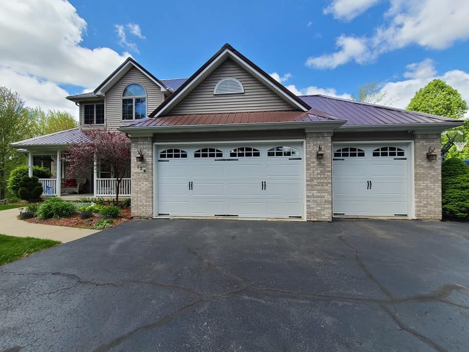 A large house with three garage doors and a purple roof