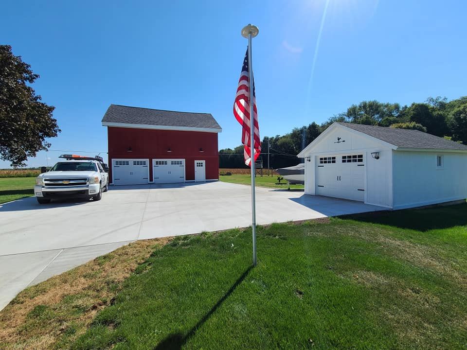 A white truck is parked in front of a red barn