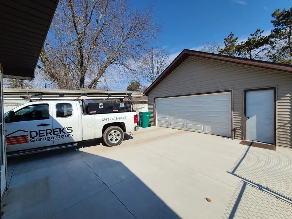 A white truck is parked in front of a garage door.