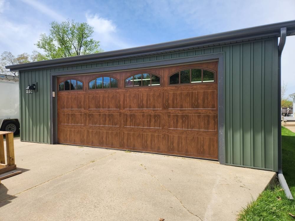 A green garage with a large wooden garage door.