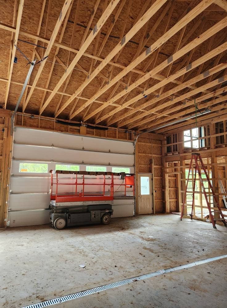 A garage under construction with a large garage door and a scissor lift.