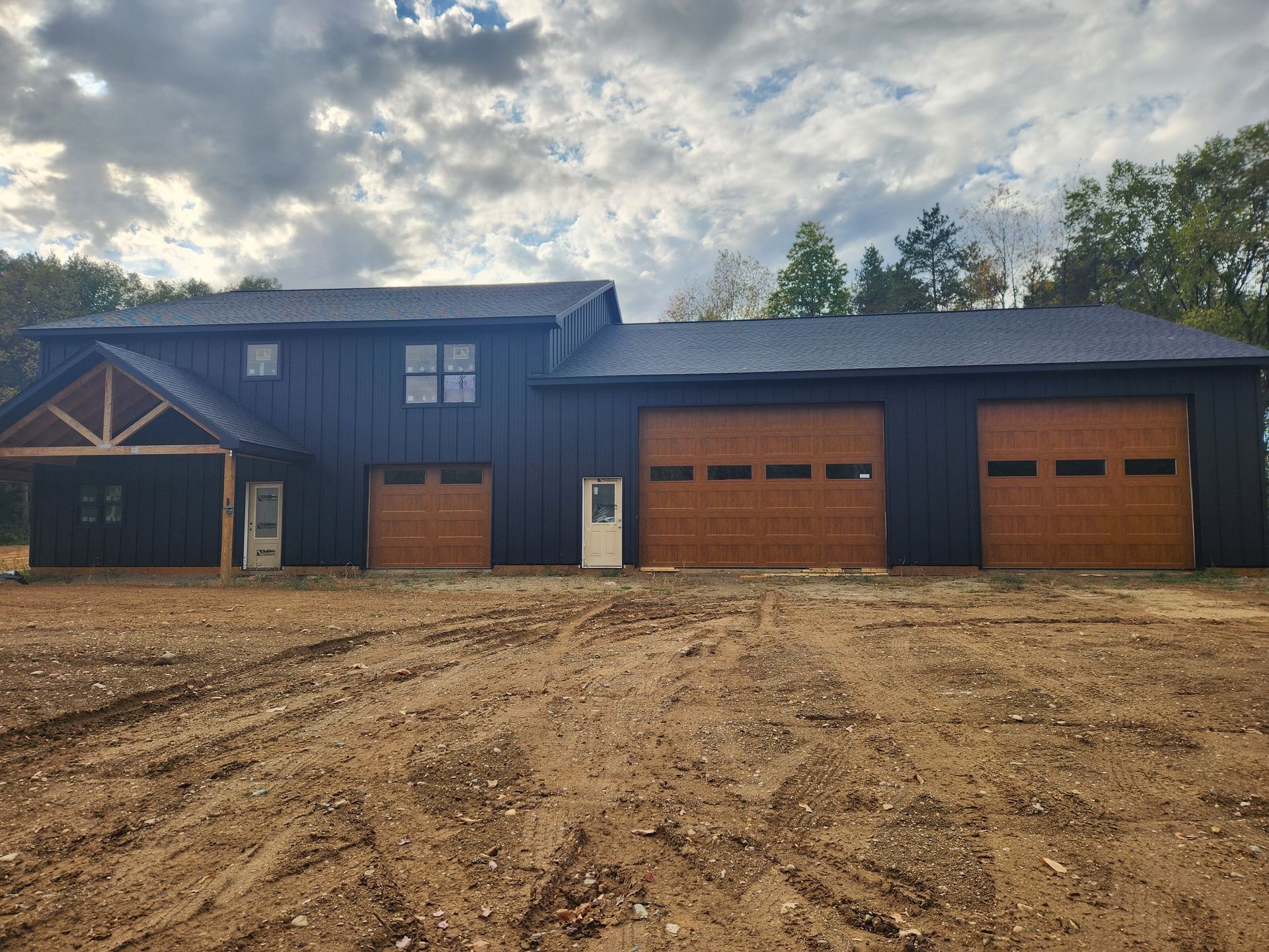 A large house with two garage doors is sitting on top of a dirt field.