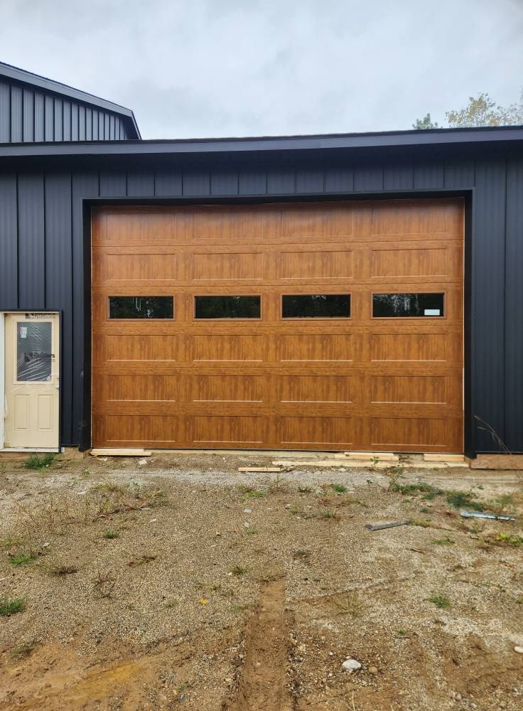 A large wooden garage door is sitting in front of a black building.